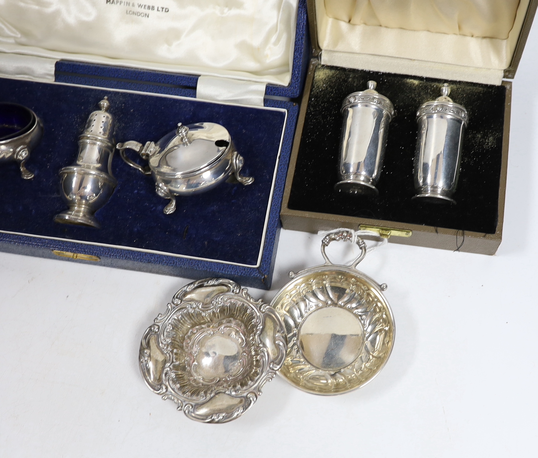 An Elizabeth II cased silver three piece condiment set by Mappin & Webb, a cased pair of Irish silver pepperettes, a cased set of six silver coffee spoons, two silver dishes and a silver mounted photograph frame.